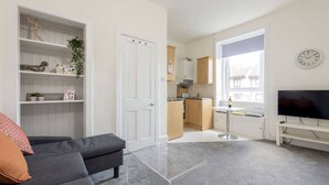 A compact living space with a sofa, a TV, a kitchen area, and a dining table. - Balfour · Stylish and Comfortable City Centre Apartment (Edinburgh)