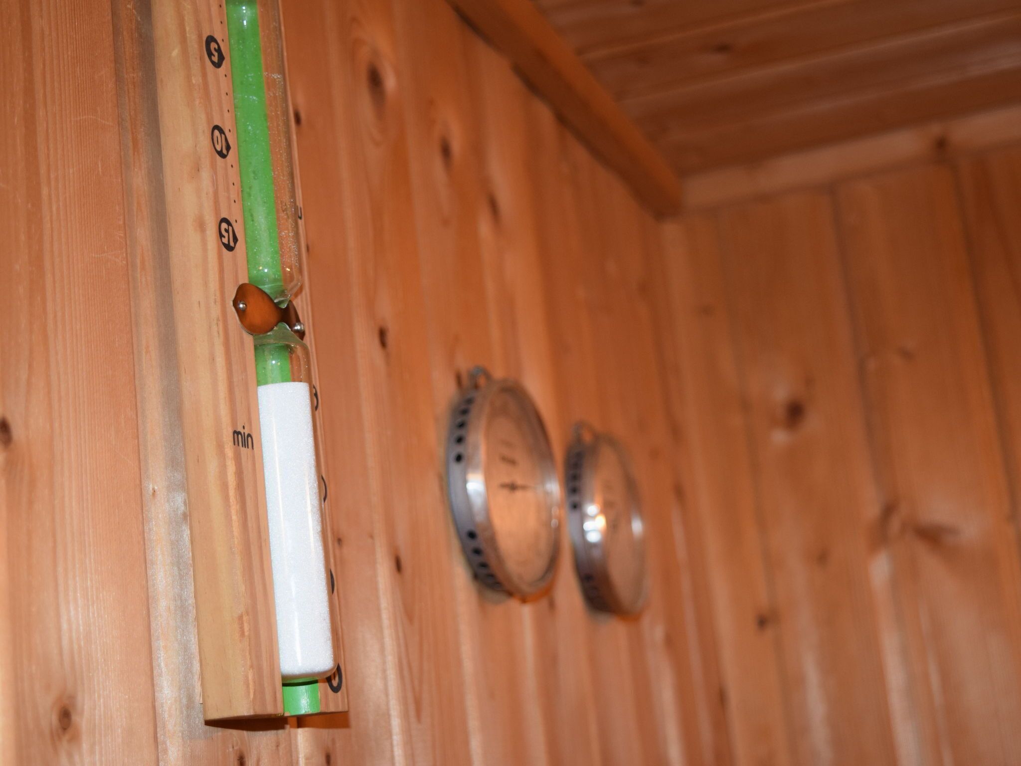 A wooden wall with a green and white switch and two clocks.
