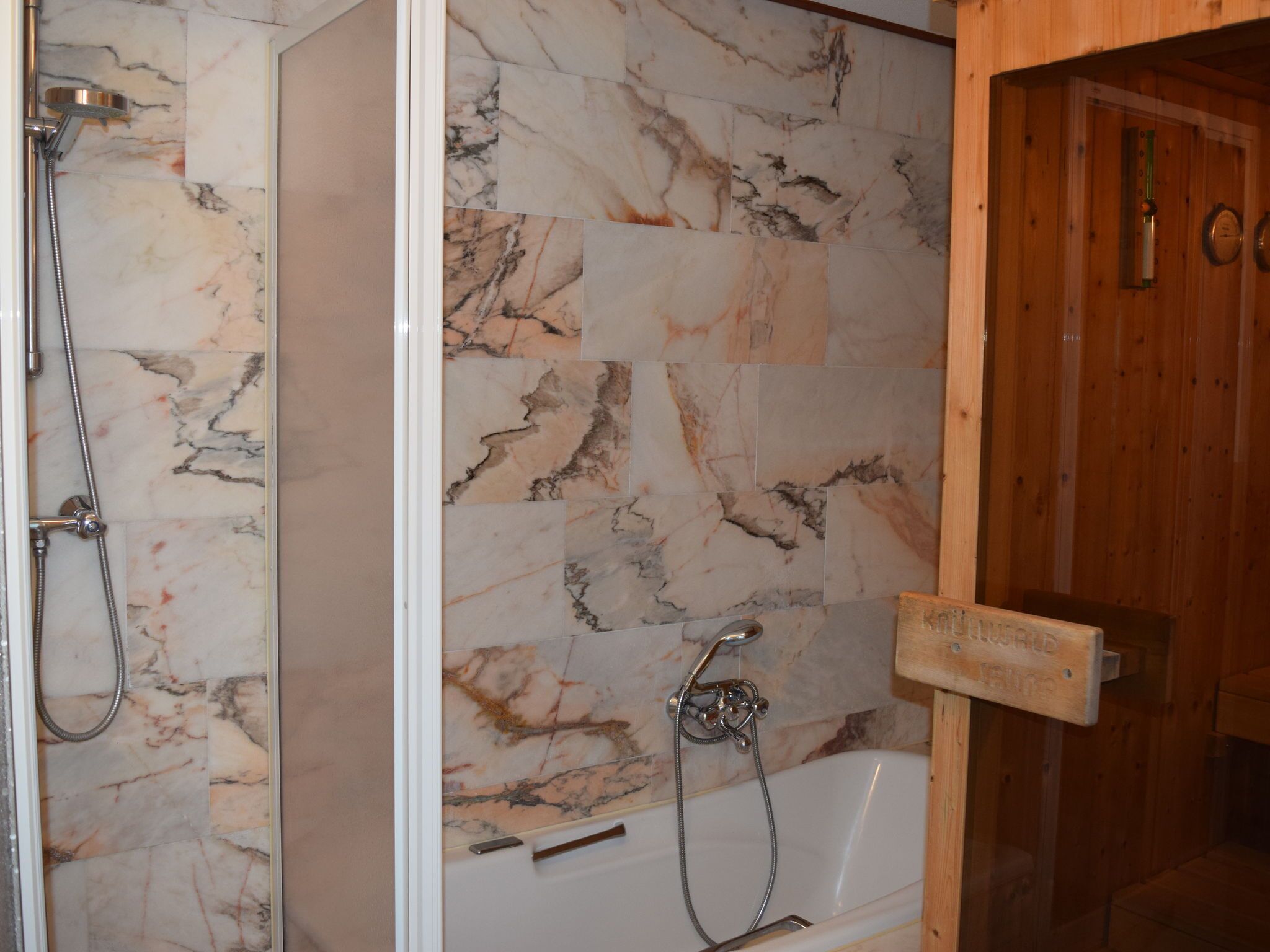 Une salle de bain avec une douche, une baignoire et une porte en bois.