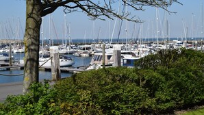 Un port de plaisance où de nombreux bateaux sont amarrés, entouré de verdure et sous un ciel dégagé.