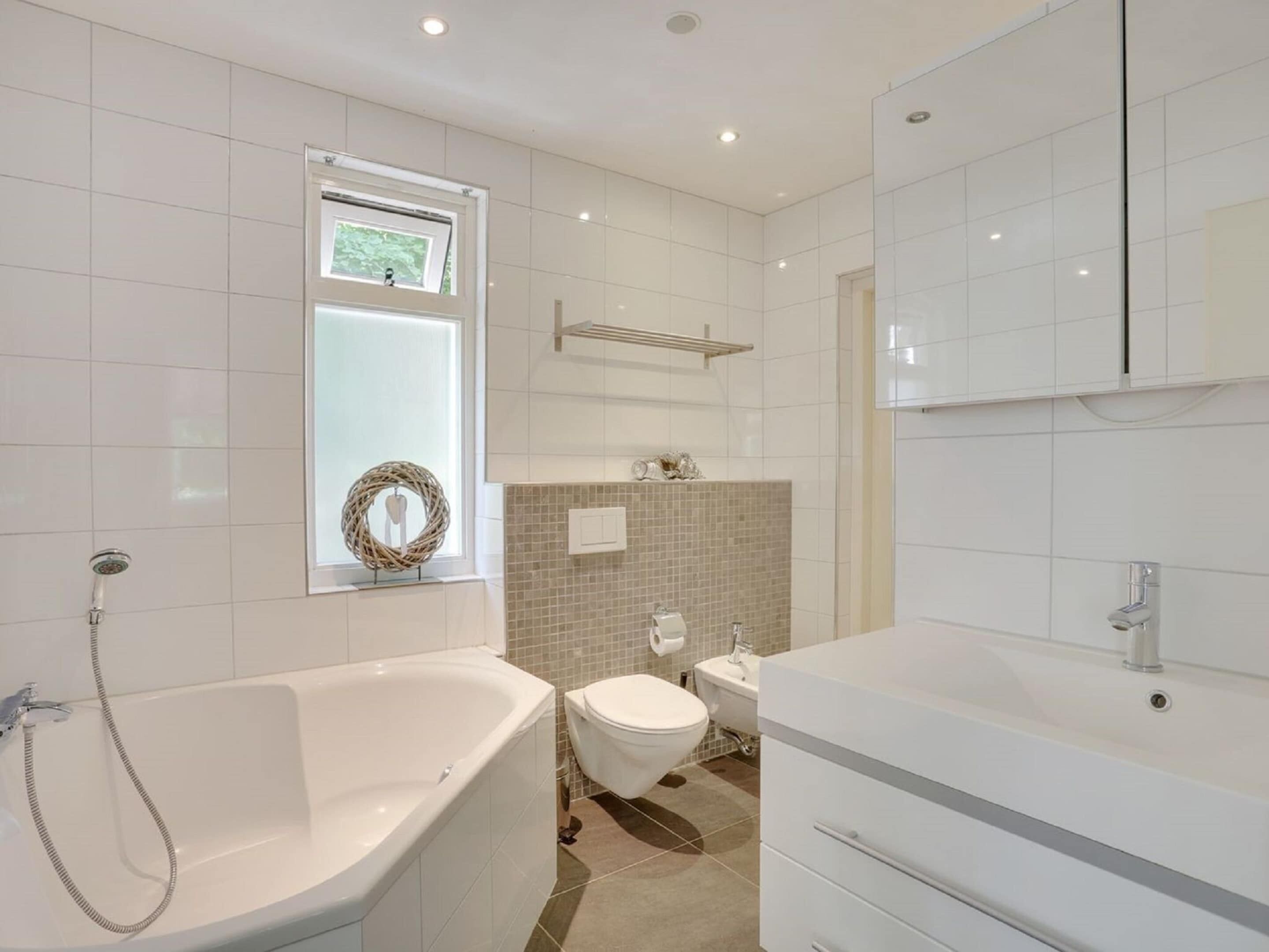 Ein modernes Badezimmer mit freistehender Badewanne, Toilette und Waschbecken.