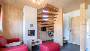 Een modern interieur met een houten trap, een rode bank, een kleine tafel en een aan de muur bevestigde televisie.