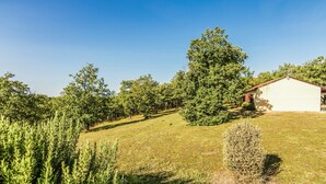 Een huis met een schuin dak, omgeven door een gazon en bomen.