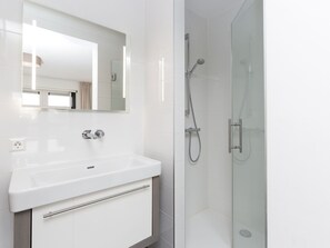 A modern bathroom with a white sink, a mirror, and a glass-enclosed shower area. - Friesland Villa With Fireplace (Delfstrahuizen)