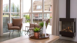 A modern living room with large windows, a fireplace, and a dining area. - Friesland Villa With Fireplace (Delfstrahuizen)
