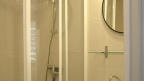 A bathroom with a glass-enclosed shower, a sink with a modern faucet, and a mirror above the sink.