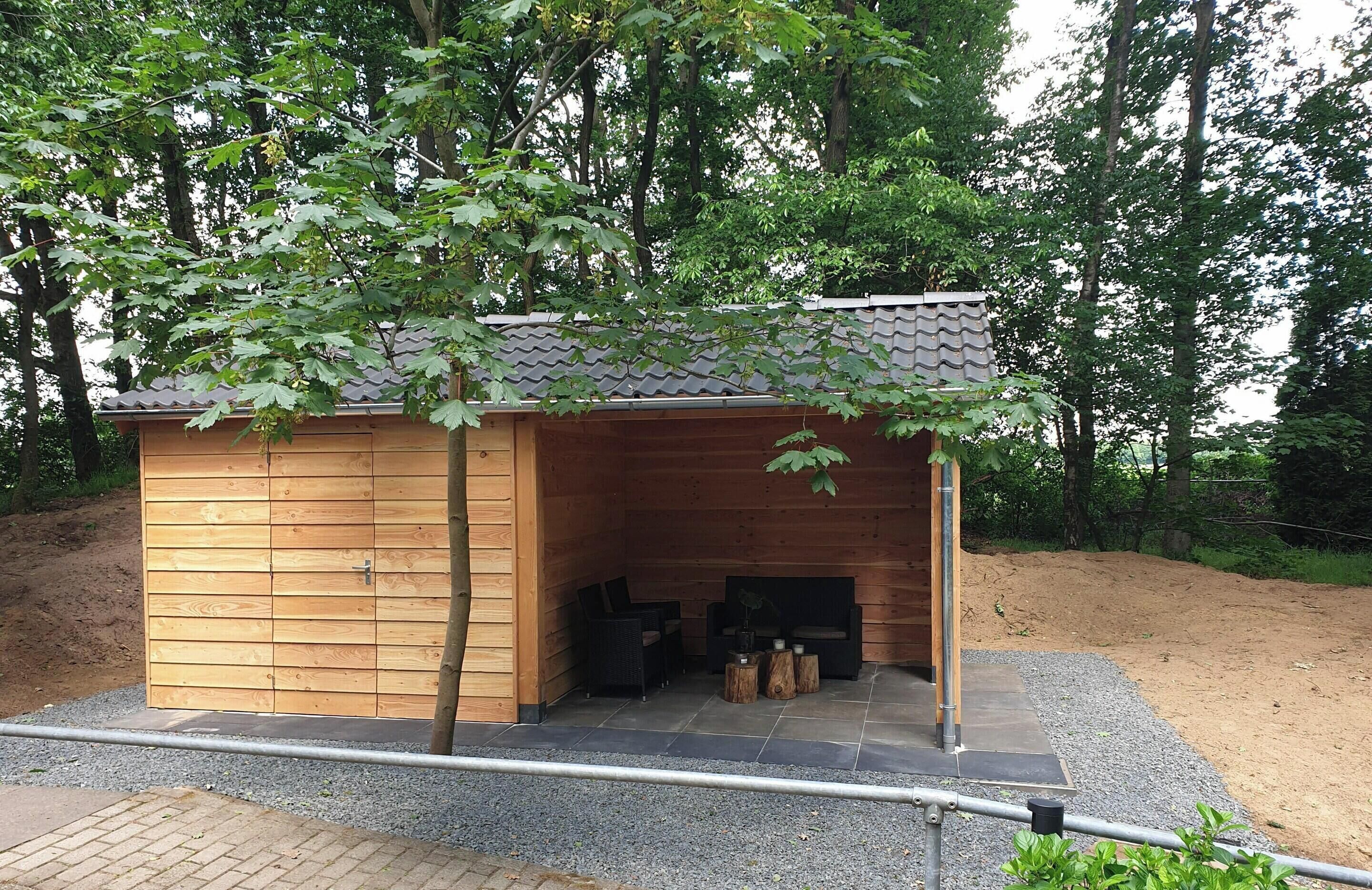 A wooden cabin with a tiled roof, a fireplace, and a seating area with chairs and a table.