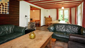 Un ampio soggiorno con divani in pelle, un tavolino in legno e un'area pranzo con tavolo e sedie in legno.