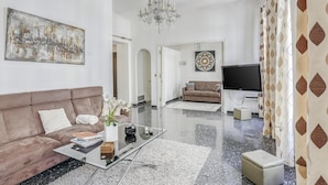 A modern living room with a sofa, coffee table, TV, and artwork. - Apartment in Nice Near Beaches (Nice)