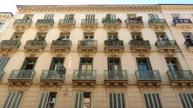 A multi-story building with ornate balconies, green shutters, and potted plants. - Apartment in Nice Near Beaches (Nice)
