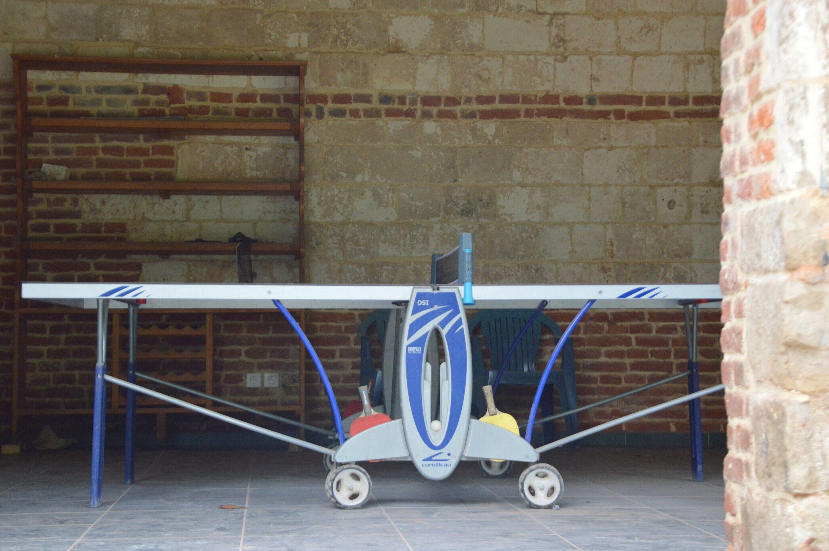 Petit avió sobre un suport transportable amb rodes, amb un mur de maons al fons.