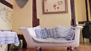 A cozy room with a white sofa, a table with a striped tablecloth, and a wall decorated with heart-shaped items. - Apartment in Riquewihr With Terrace (Riquewihr)