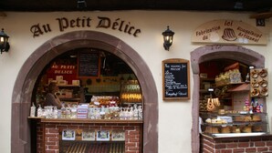 A bakery named 'Au Petit Délice' with a brick facade, a display case of baked goods, and a sign indicating 'Fabrication du Kougelhopf Artisanal.' - Apartment in Riquewihr With Terrace (Riquewihr)
