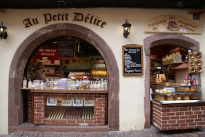 A bakery named 'Au Petit Délice' with a brick facade, a display case of baked goods, and a sign indicating 'Fabrication du Kougelhopf Artisanal.' - Apartment in Riquewihr With Terrace (Riquewihr)