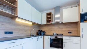 Una cocina moderna con armarios blancos, un salpicadero de madera y un horno empotrado.