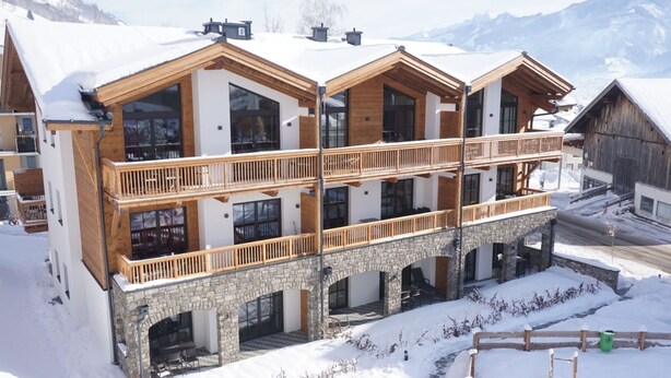Un hotel de varios pisos con base de piedra y niveles superiores de madera, con balcones y ventanas amplias.