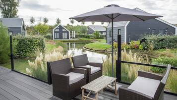 A deck with wicker furniture, a table, and an umbrella.