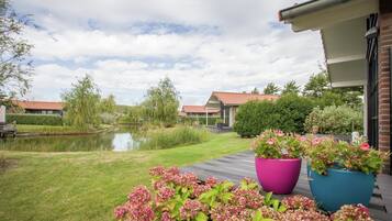 A garden with a pond, potted plants, and a wooden deck.
