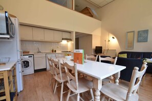 A kitchen with white cabinets, a dining table with chairs, a washing machine, and a box labeled 'Belvilla.' - Holiday Home in Bergen Near North Sea Beach (Bergen aan Zee)