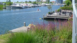 A marina with boats docked, a dock with seating, and a waterway. - Water Villa Kortgene by Veerse Meer (Kortgene)