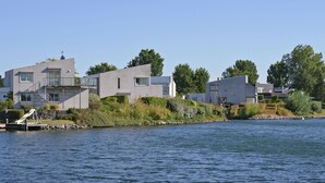 A modern waterfront property with a dock, a small boat, and a staircase leading to a balcony. - Water Villa Kortgene by Veerse Meer (Kortgene)