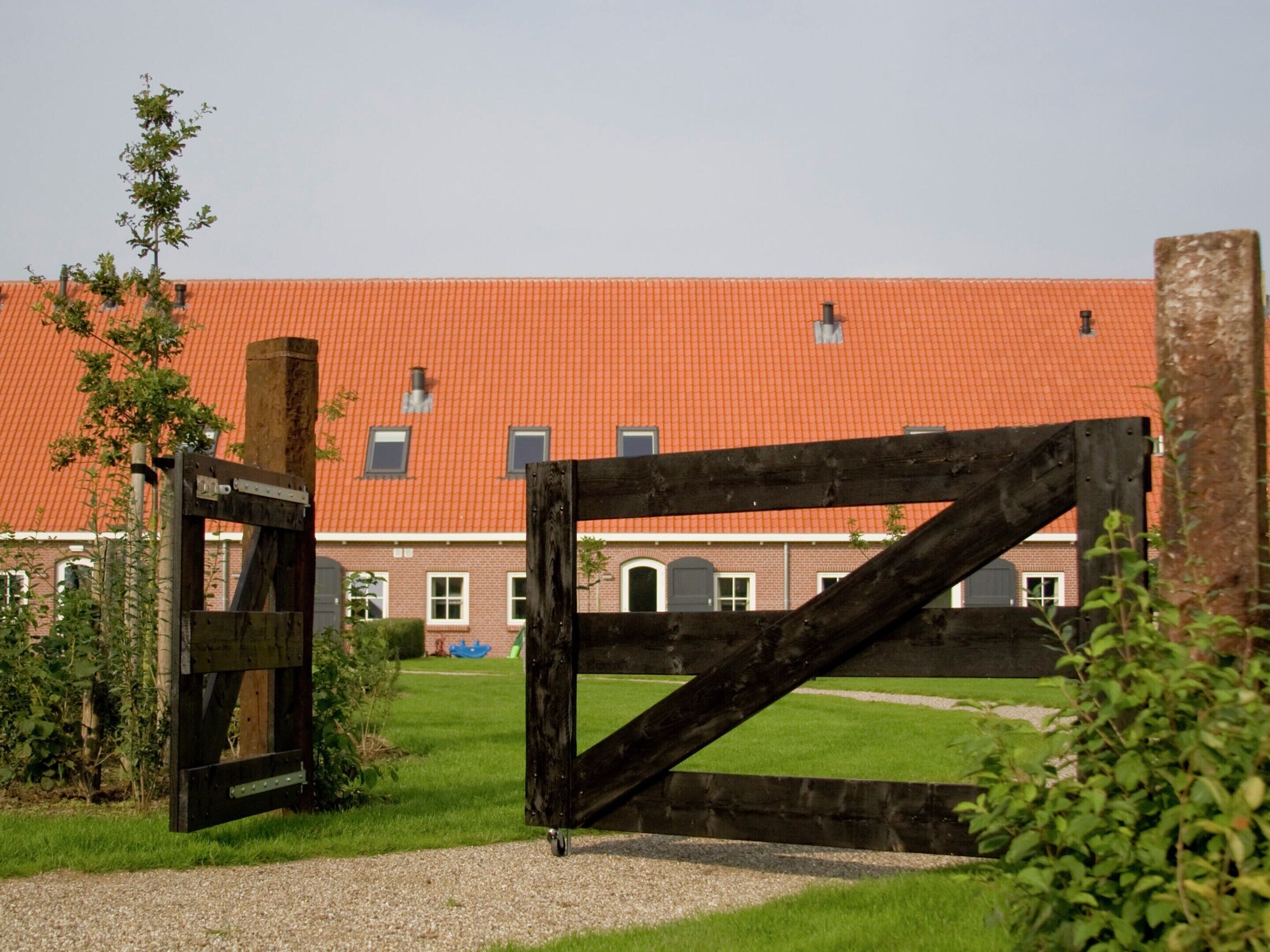 A building with a red-tiled roof and a wooden gate in the foreground.