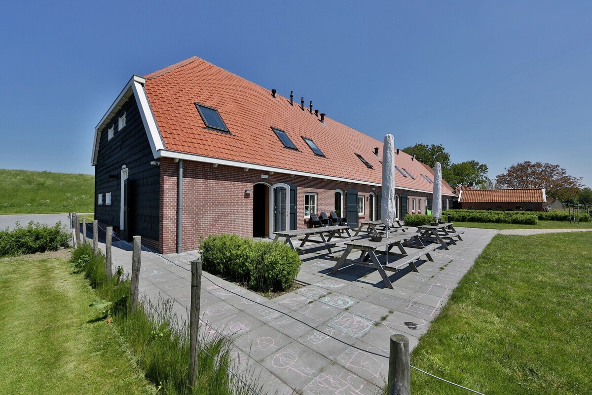 A building with a red-tiled roof, a brick facade, and a patio area with picnic tables.