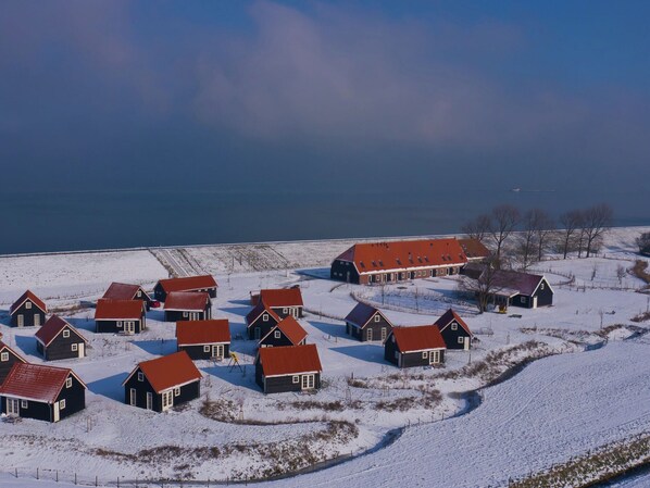 A cluster of traditional houses with red roofs, surrounded by snow-covered fields and a body of water in the background. - Wemeldinge Group Retreat (Wemeldinge)