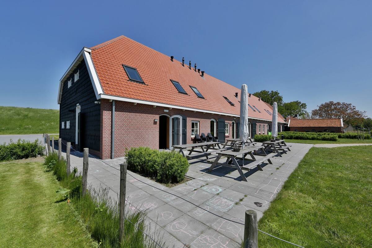 A building with a red-tiled roof, a brick exterior, and a patio area with picnic tables.
