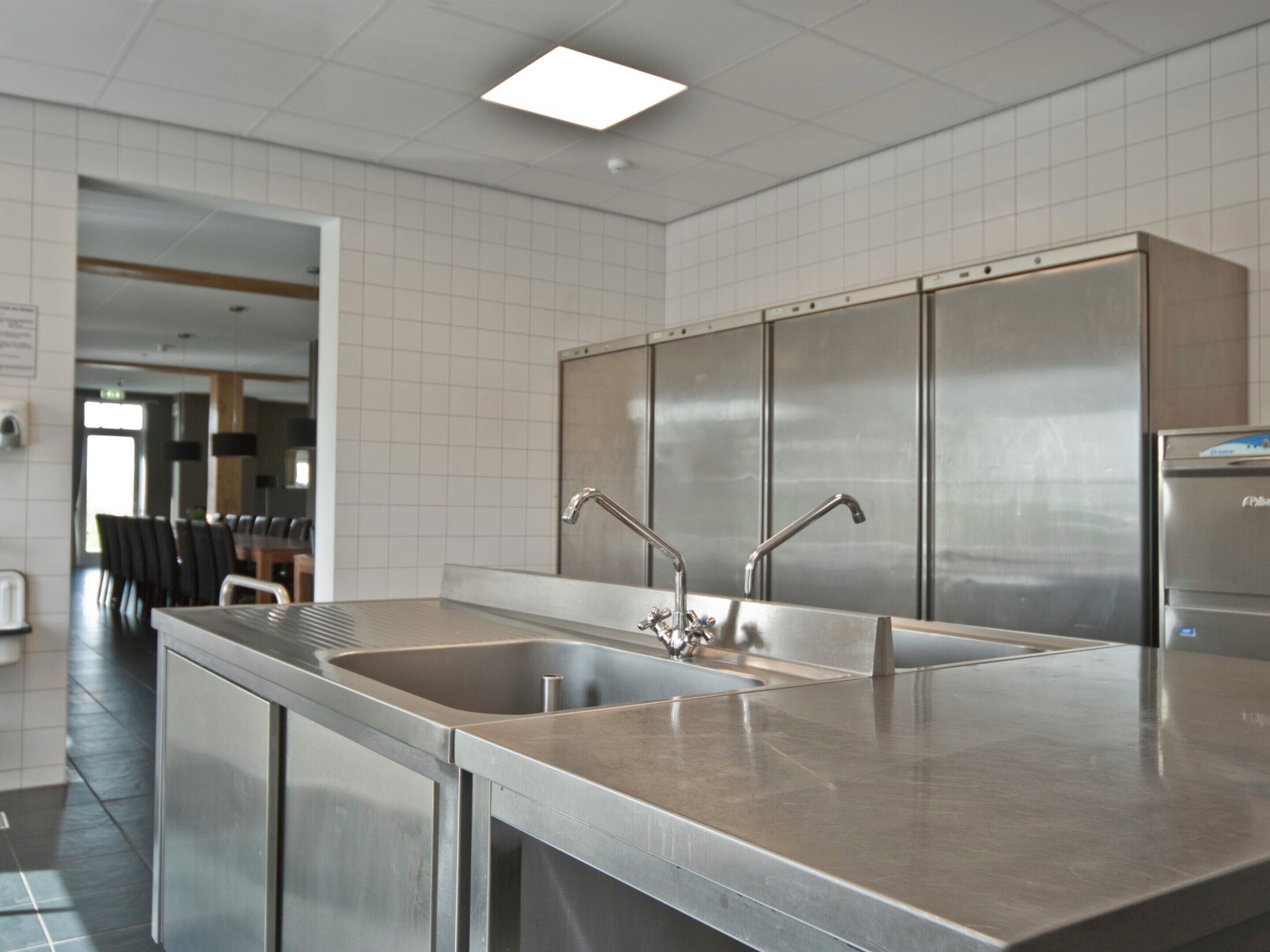 A modern kitchen with stainless steel appliances, two sinks, and a large refrigerator.