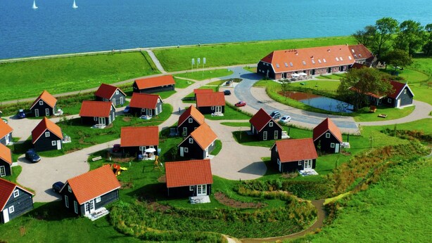 Ein Küstendorf mit traditionellen Häusern, einem großen Schuppen und Blick auf das Meer.