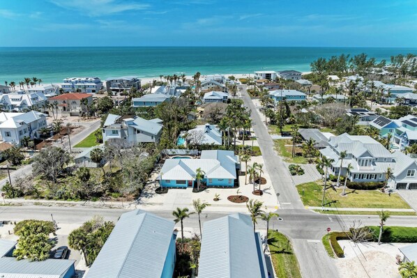 A coastal residential area with houses, palm trees, and a view of the ocean.