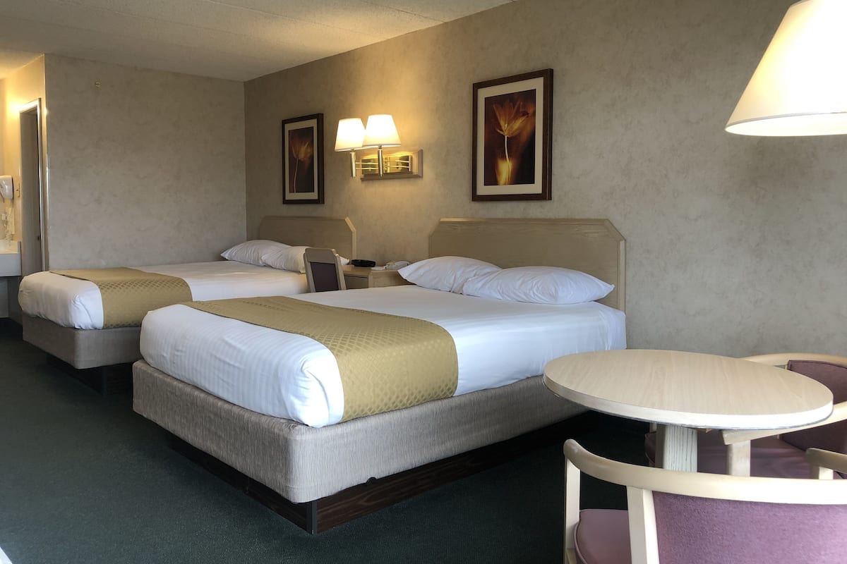Ein Hotelzimmer mit zwei Betten, einem kleinen Tisch und zwei Wandleuchten.