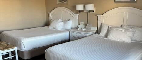 A hotel room with two single beds, a small table, and two bedside lamps.