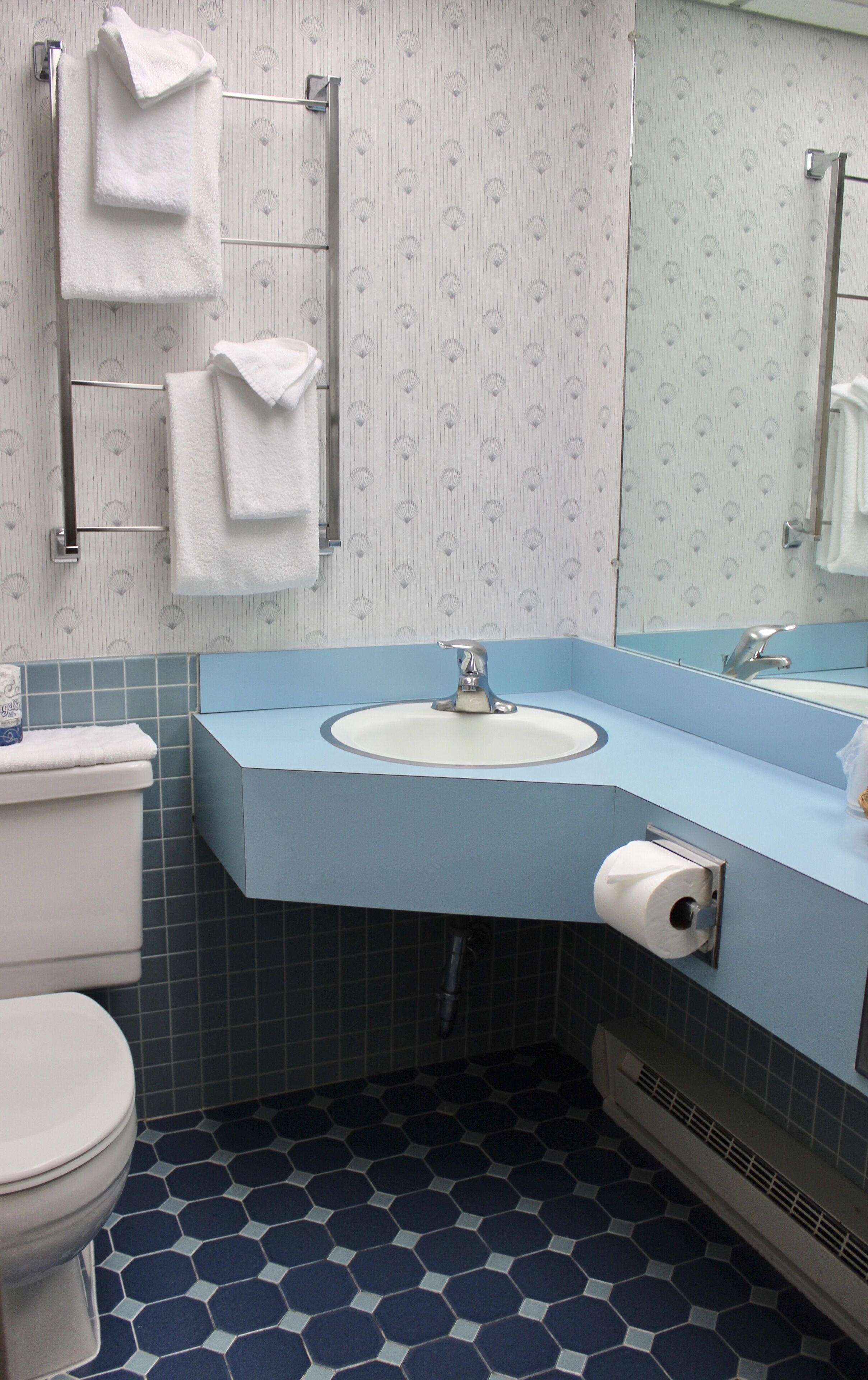 A bathroom with a toilet, sink, and towel rack.
