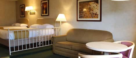 A hotel room with two beds, a sofa, a small table, and two chairs.