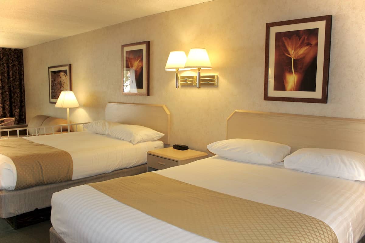 Ein Hotelzimmer mit zwei Betten, einem Nachttisch, einer Lampe und Wandleuchten.