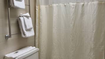 A bathroom with a toilet, a towel rack with towels, and a shower curtain.