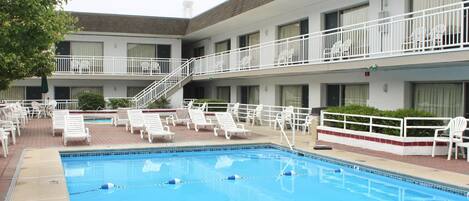 A hotel with a swimming pool, multiple balconies, and outdoor seating areas.