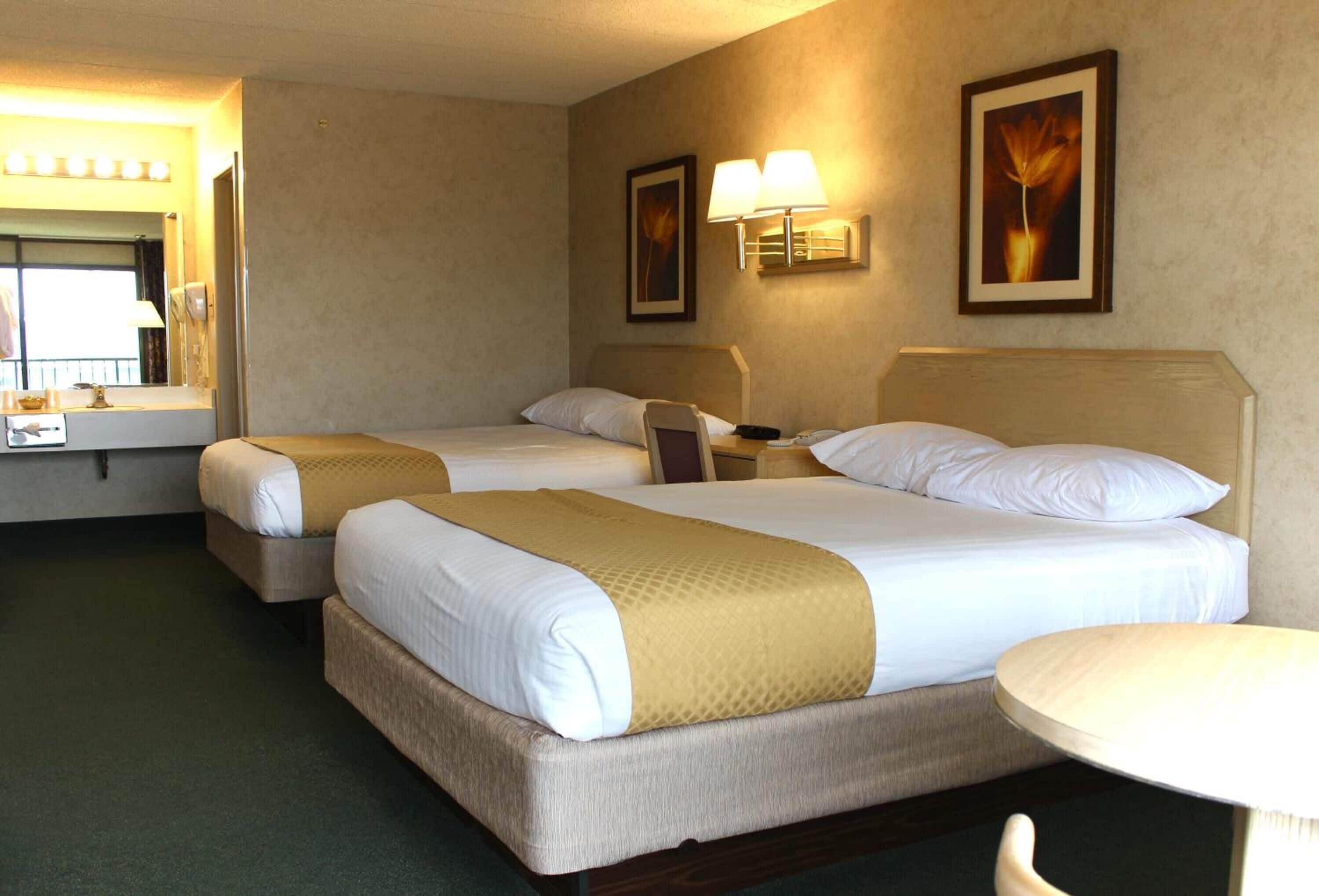 Ein Hotelzimmer mit zwei Betten, einem kleinen Tisch, einem Stuhl, einem Spiegel und Wandlampen.