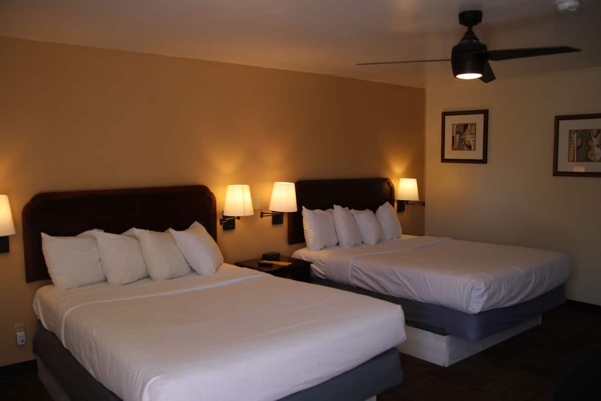 Ein Hotelzimmer mit zwei Betten, jeweils mit Kopfstütze und Nachttischlampen.