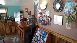 A bar area with wooden furniture, a refrigerator, and a display of books. - Townhouse Motel (Lusk)