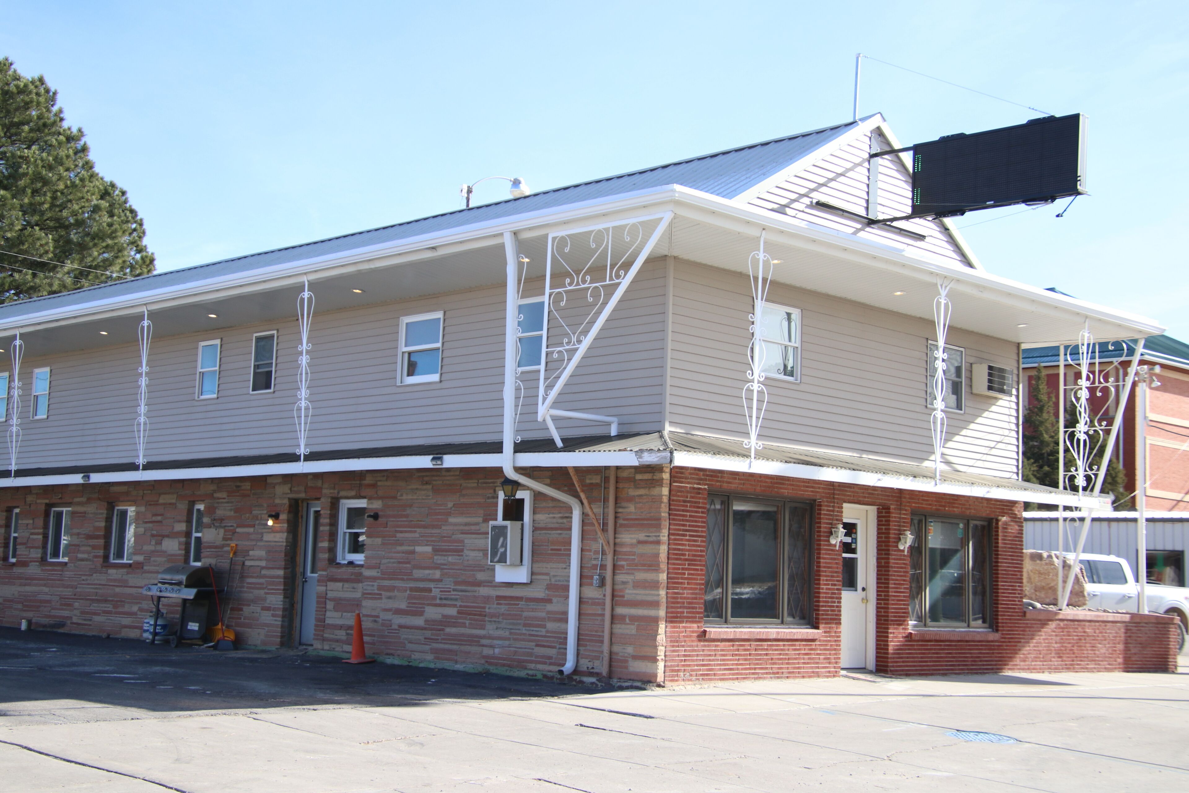 A two-story building with a flat roof, a brick base, and a white exterior.