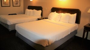 A hotel room with two beds, each with white linens and headboards. There are framed pictures on the wall and a lamp on the nightstand. - Townhouse Motel (Lusk)