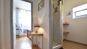A hallway with a wooden floor, a table with a lamp, a glass shower enclosure, and a door leading to another room. - Villa in Crux-la-ville Near Morvan Park (Crux-la-Ville)