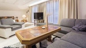 A modern living room with a sofa set, a coffee table, a TV, and a lamp. - Holiday Home in Rennweg Near Ski Slopes (Rennweg am Katschberg)