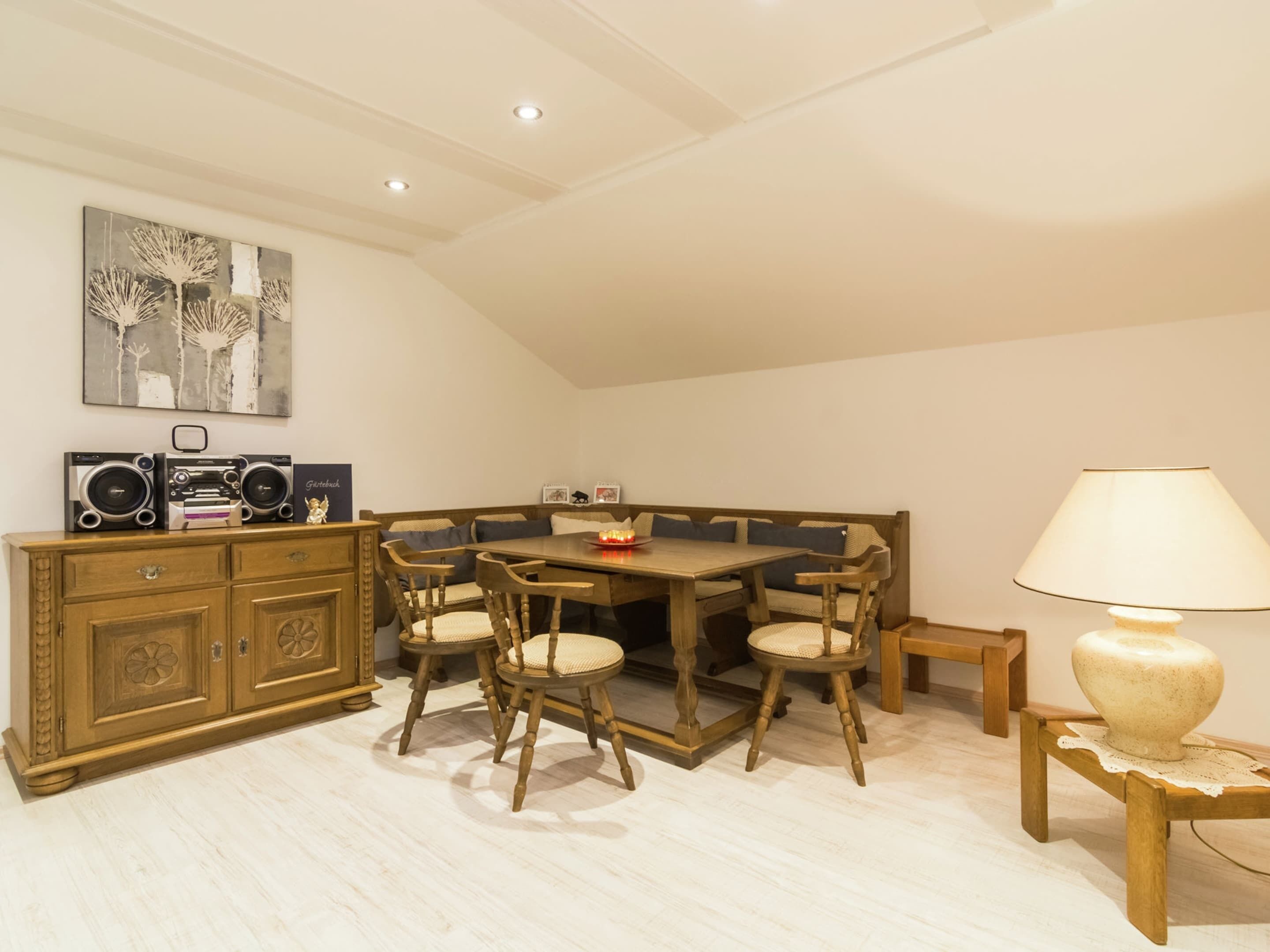 A dining area with a wooden table and chairs, a cabinet with decorative items, and a lamp on a side table.