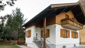 A two-story house with a white exterior and wooden shutters, a balcony, and a stone staircase leading to the entrance. - Holiday Home in Rennweg Near Ski Slopes (Rennweg am Katschberg)