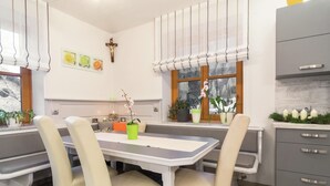 A modern kitchen with a dining area, featuring a table with chairs, a window with curtains, and a cross on the wall. - Holiday Home in Rennweg Near Ski Slopes (Rennweg am Katschberg)