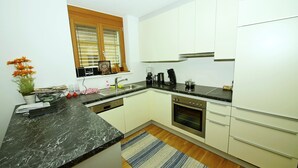 A modern kitchen with white cabinets, a black countertop, and a built-in oven. - Vibrant Apartment near Ski Slopes in Brand (Brand)
